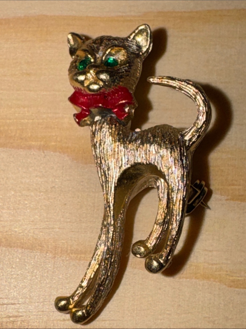 Vintage gold-tone articulated cat brooch with green eyes and a red bow